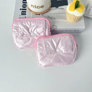Close-up of pink quilted mini pouches with heart and bow patterns and glossy finish