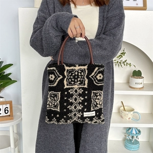 Detail of plush tote bag with ethnic patterns and brown leather-like ring handles