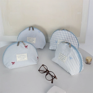 Detail of light blue striped and checkered cosmetic bags with delicate bow embroidery