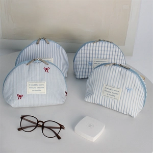 Detail of blue striped and checkered cosmetic bags with embroidered bow and metal zipper