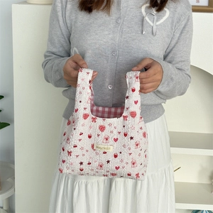 Detail of white bubble textured handbag with red heart and strawberry patterns