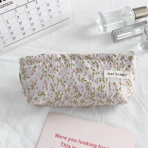 Close-up of floral canvas pouch with pink flower embroidery and branded woven label