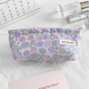 Close-up of small floral canvas makeup bag with purple roses and metal zipper detail