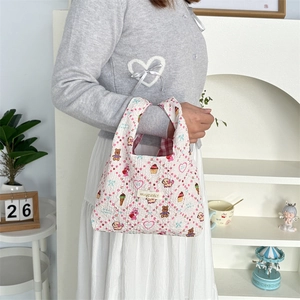 Detailed view of white quilted handbag with cute cartoon bear and dog patterns