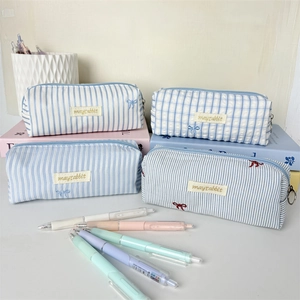 Close-up of four assorted blue striped and plaid canvas pencil cases with rabbit labels.