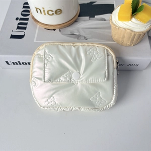 Detail of white pearlescent quilted PU coin purse with stitched bow pattern and snap pocket
