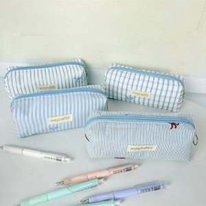 Close-up of light blue striped and checkered canvas pencil cases on white desk