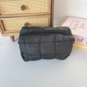 Detail shot of the black quilted fabric texture and zipper on the large makeup bag