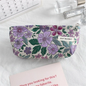 Detail of floral jacquard fabric makeup bag with silver zipper and woven logo tag