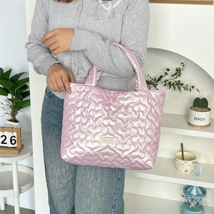 Detail view of pink heart-quilted tote bag fabric and brand label in lifestyle scene