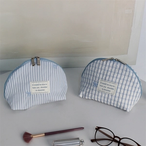 Detailed view of light blue embroidered shell cosmetic bags with cute bows and dual zippers