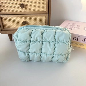 Detailed texture of mint green quilted makeup bag with soft bubble puff fabric and zipper