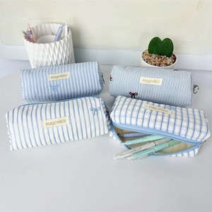 Detail view showing light blue striped and checkered pencil cases with various pens