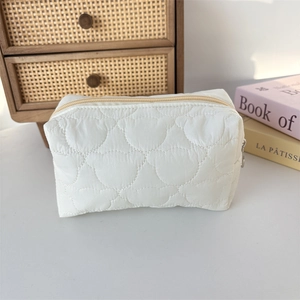 Detailed close-up of white quilted cosmetic bag with soft bear head pattern and silver zipper
