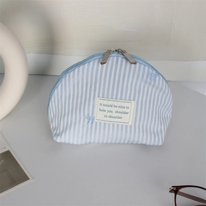 Close-up of blue striped canvas makeup bag with embroidered bows and dual zippers