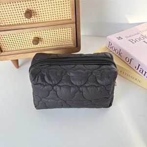Close-up of black quilted nylon toiletry bag with cute bear stitching on a wooden desk