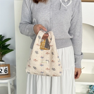 Detail of cream puff fabric handbag with elephant pattern and yellow plaid lining