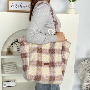 Detail of purple plaid plush tote bag with soft fleece texture and leather logo patch