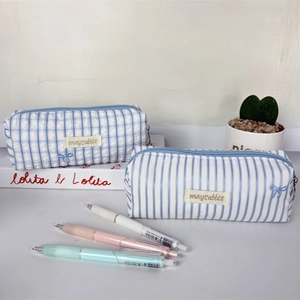 Detailed macro view of blue striped and checkered pencil cases with cute embroidery