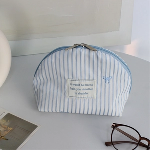 Detail of blue striped shell cosmetic bag with embroidered bow and metal dual zippers