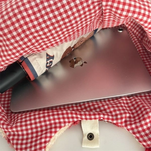Detailansicht der Innenseite der karierten Tasche mit Tablet und Regenschirm