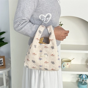 Detail of quilted texture and colorful elephant patterns on a cream casual tote bag