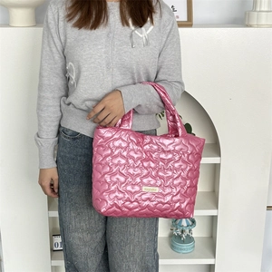 Detail view of heart-quilted texture on pink PU leather tote with brand label