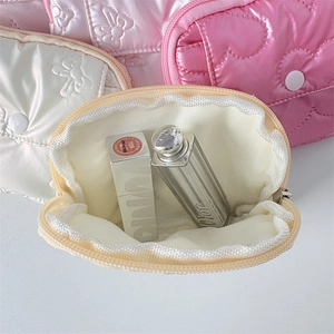 Detailed macro view of quilted satin pouches with smooth texture and zipper closure