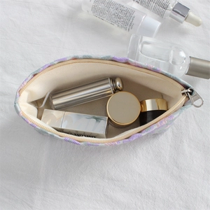 Detail shot of mini floral embroidery canvas makeup bag with beige lining and zip closure