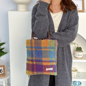 Detail of colorful plush plaid tote bag with brown leather handles and brand label