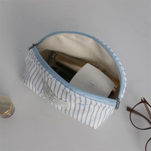 Detail of blue striped canvas makeup bag showing interior storage capacity and zipper