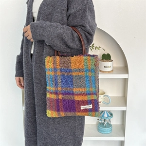 Detail of colorful plaid faux fur tote bag with brown leather handles and brand label
