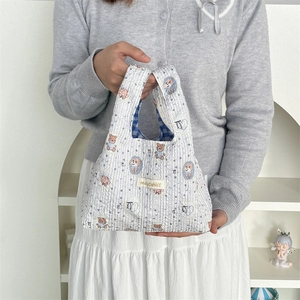 Quilted white and blue striped handbag with cute bear pattern worn by a model