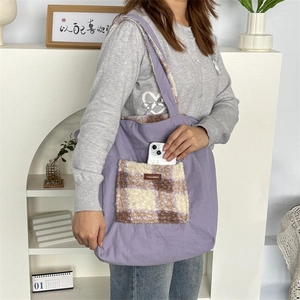 Detail of purple tote bag with checkered plush pocket and woven label on shoulder