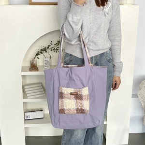 Detail of purple plush tote bag with checkered fuzzy pocket and branded label
