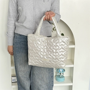 Macro shot of white heart-quilted PU handbag with brand tag and glossy pearl finish