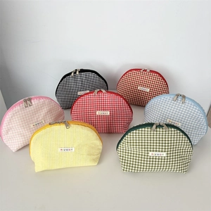 Detail of gingham shell makeup bags in various colors with metal zippers and brand labels