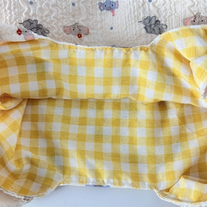 Macro detail of quilted baby fabric with elephant pattern and yellow gingham texture