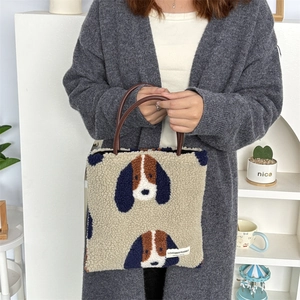 Close-up of beige plush tote bag featuring cartoon dog print and dark brown handles