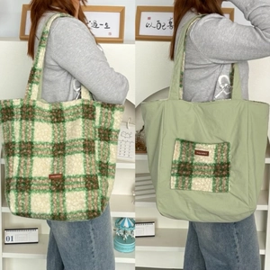 Detailed close-up of double-sided plush tote bag showing green plaid and soft fabric textures