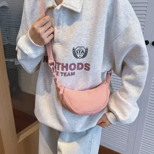 Detail of pink nylon crescent crossbody bag with adjustable strap worn by a model