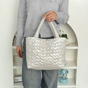Detail of white heart-quilted PU leather tote bag with soft texture and maplele label