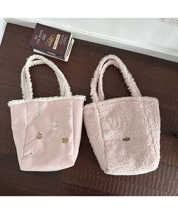 Detail of pink plush tote bags with embroidery and faux fur texture on wood background