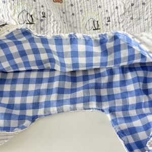Detail of blue gingham and quilted fabric with hand-drawn heart patterns on a handbag