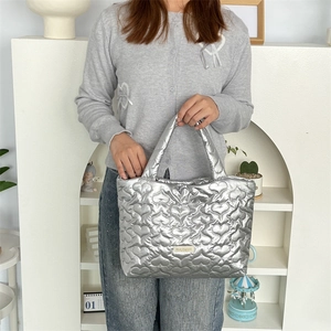 Silver heart-quilted PU tote bag detail with metallic texture and woven label