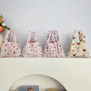 Detailed view of four quilted tote bags featuring cute animal and fruit patterns