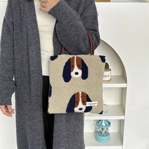Detail of plush fleece tote bag featuring cartoon dog print and brown leather handles