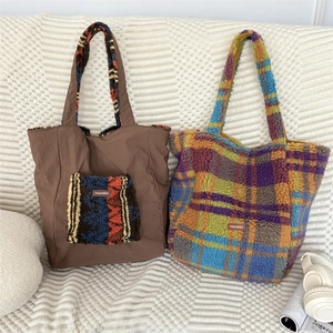 Detail of plush brown tote and blue plaid faux fur bag on white textured sofa