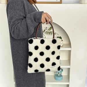 Detailed view of plush polka dot tote bag with leather handle and white fabric label