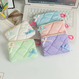 Quilted macaron color coin purses with bow details on a laptop keyboard workspace